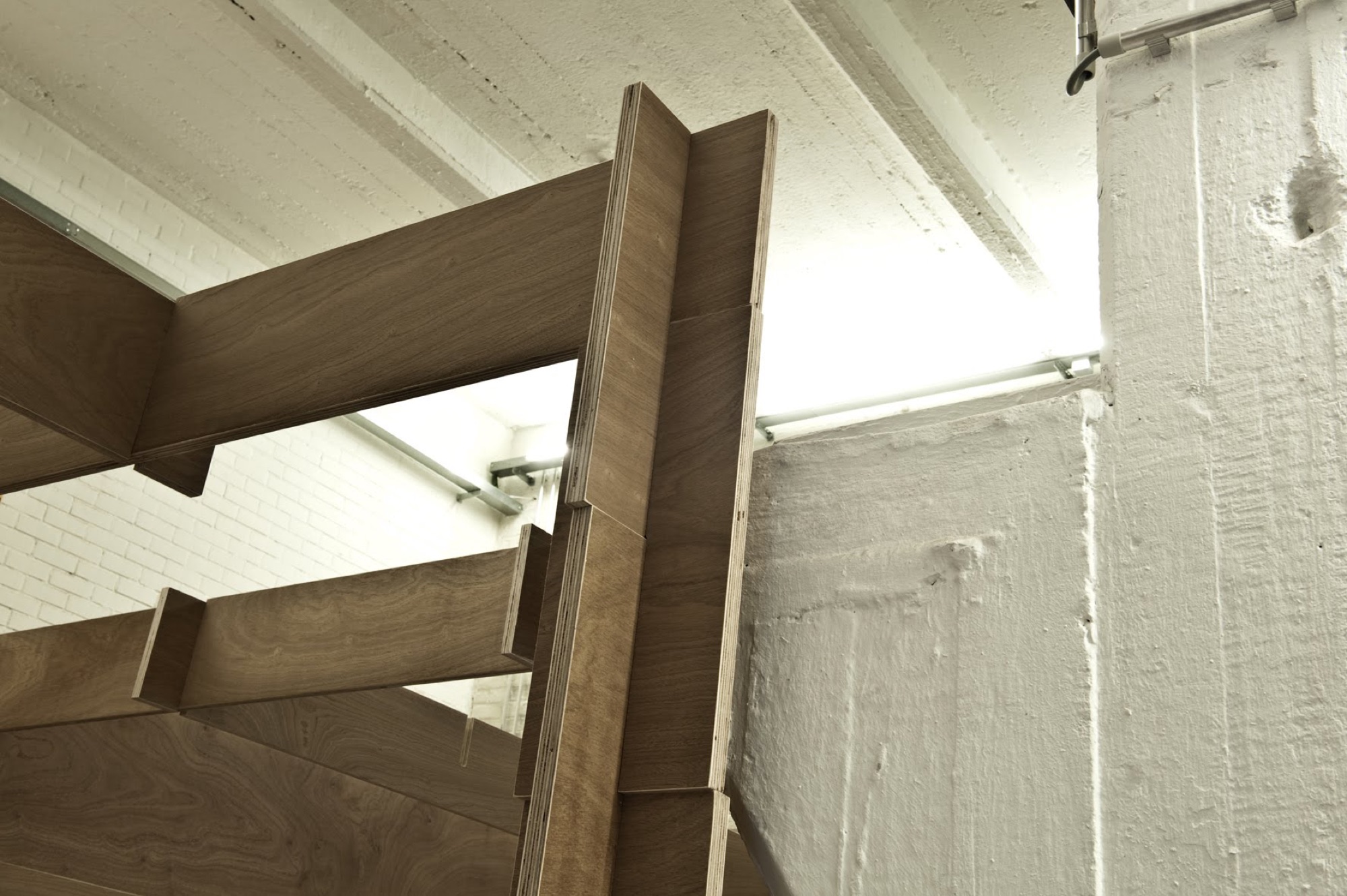 Detail van een houtverbinding in het moduleframe van BUDA.lab, opgebouwd tegen het witte plafond van de oude fabriek