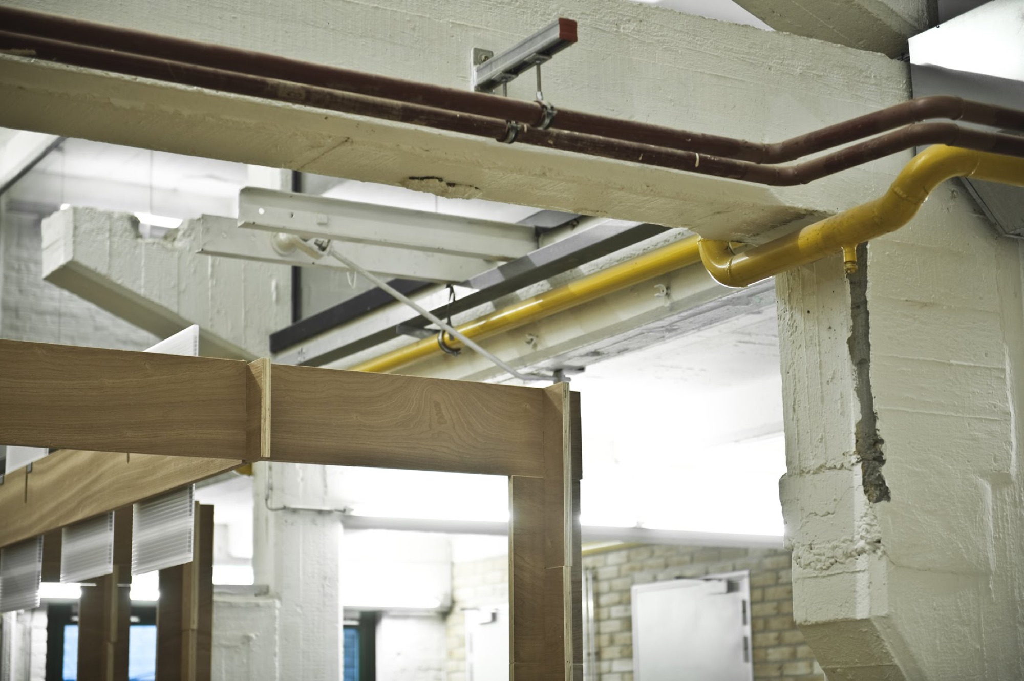 Technieken en leidingen onder het behouden betonnen plafond van BUDA.lab, met de houten module ervoor