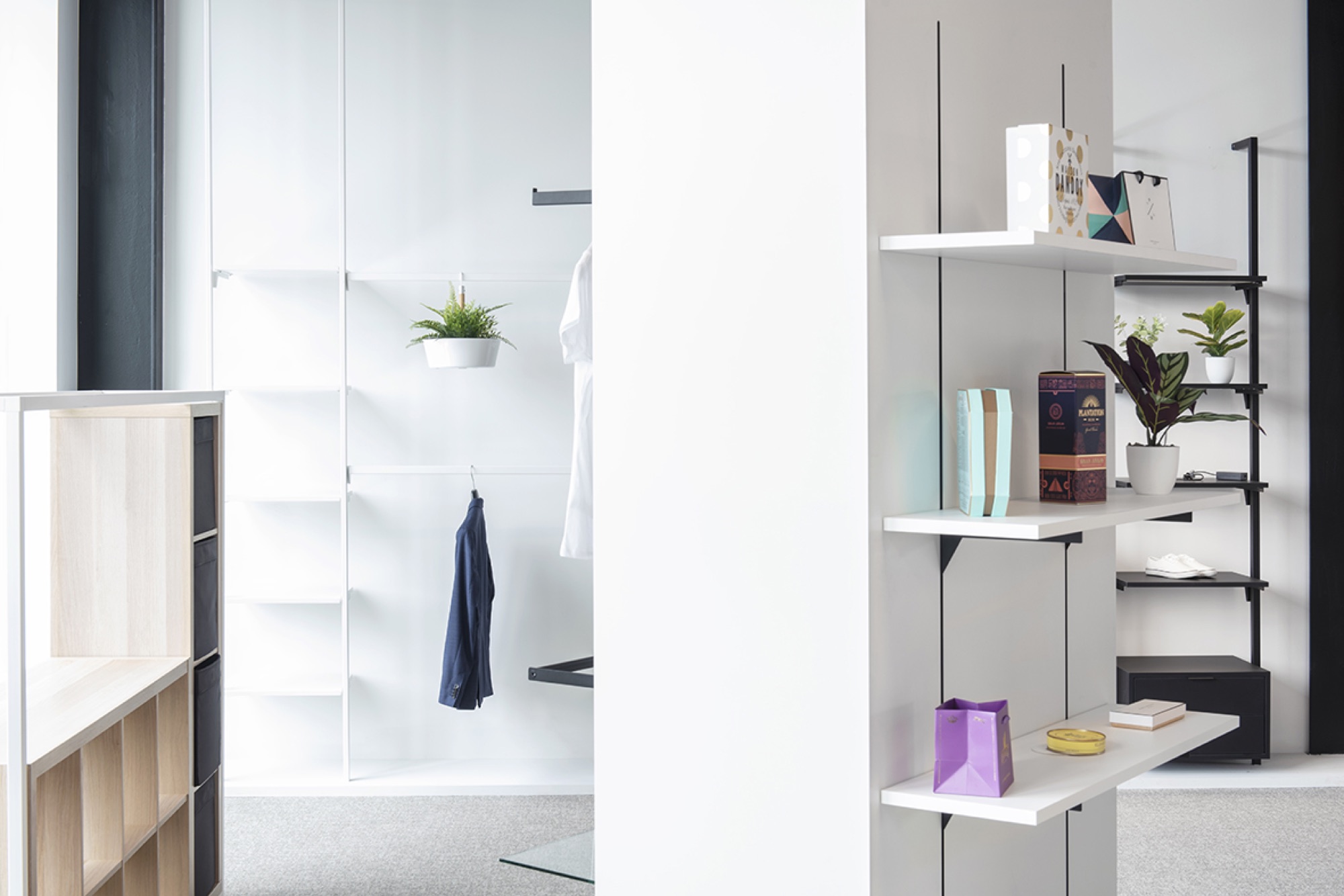 Detail in de showroom van Helbig met een wandrek met producten rechts en een witte paszone met kledingstukken achter een scheidingswand