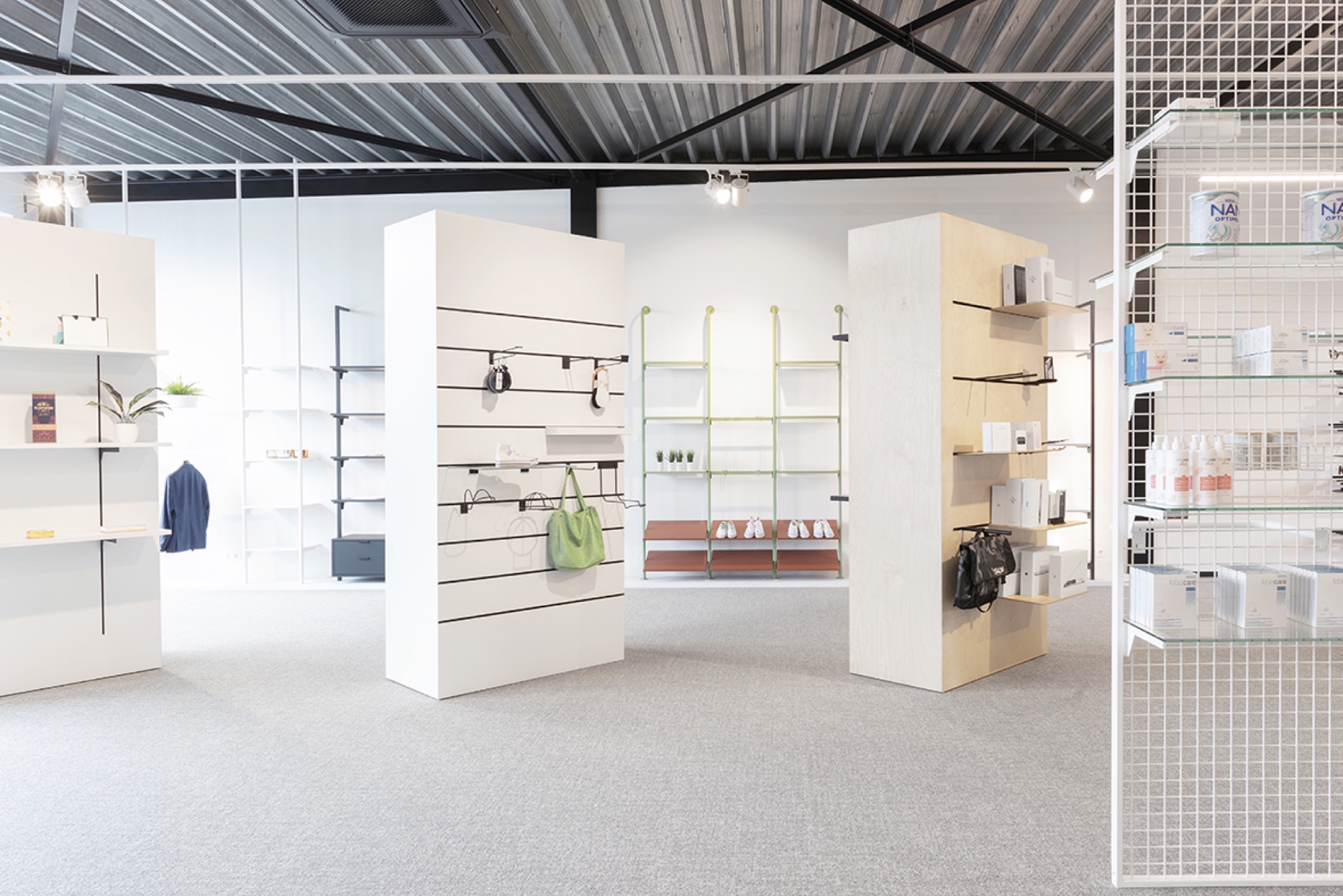 Showroom van Helbig met vrijstaande witte presentatievolumes met wandrails, open rekken en een zwarte dakstructuur boven