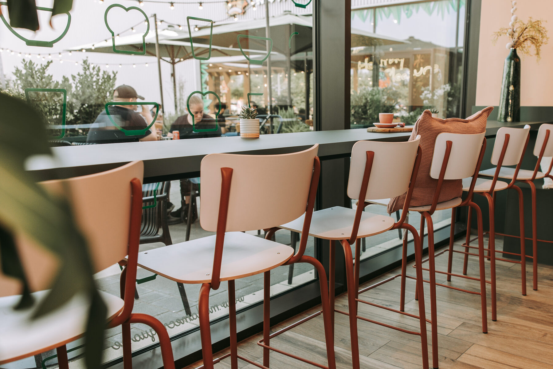 Rij barkrukken aan een smalle raamtafel bij Madame Croqu'o, met zicht op het terras