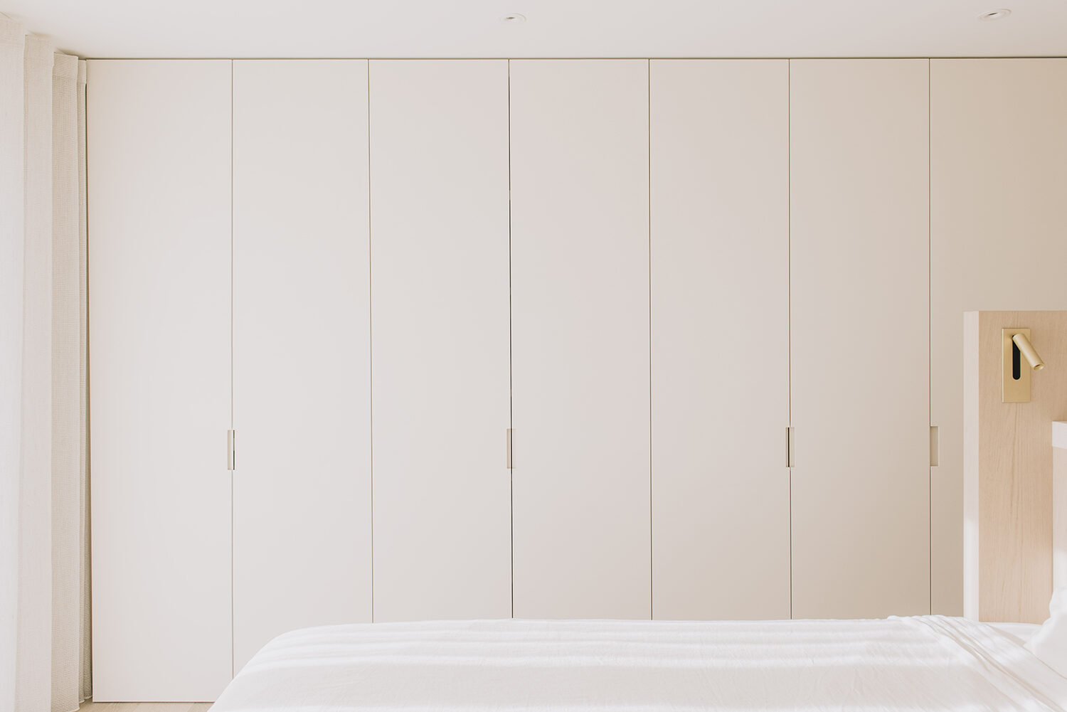 Slaapkamer in het penthouse in Nieuwpoort met een vlakke kastenwand in gebroken wit met smalle verticale grepen